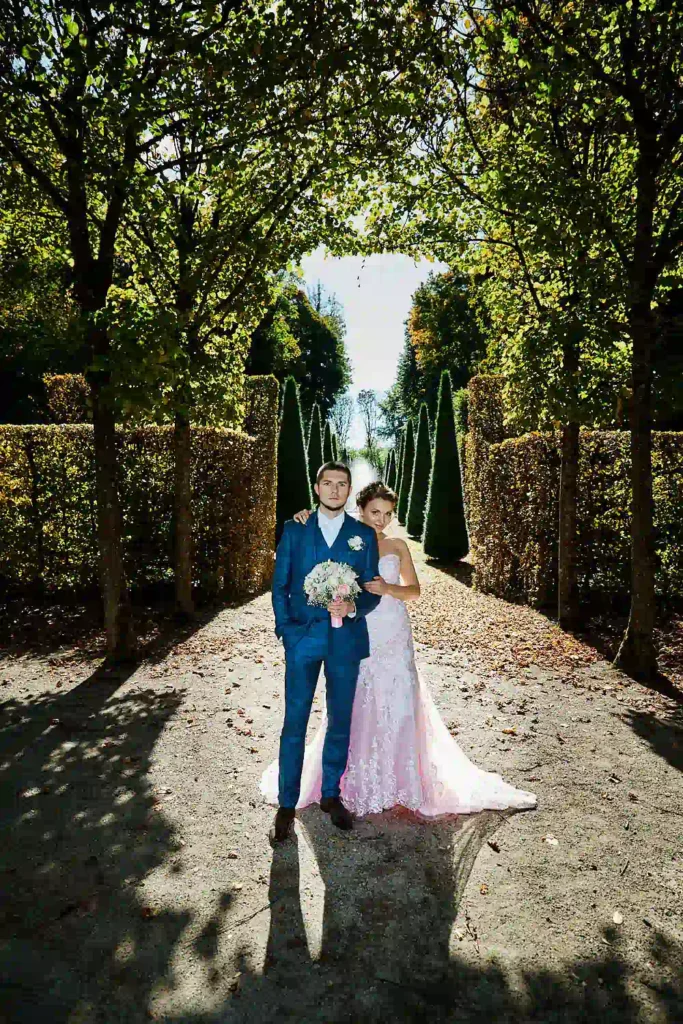 Eine Braut im rosafarbenen Hochzeitskleid und ein Bräutigam im blauen Anzug.